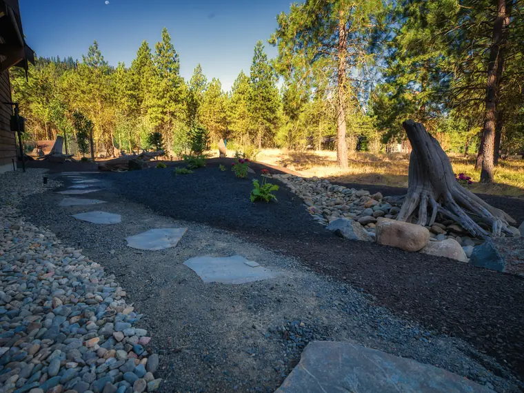 Flagstone stepping-stone path through river rock and mulch beds