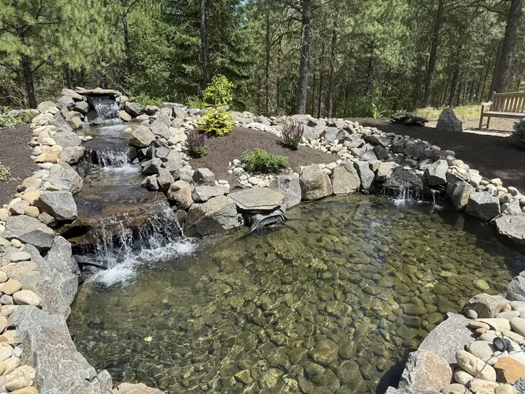 Water spilling over stacked stone into a clear pond