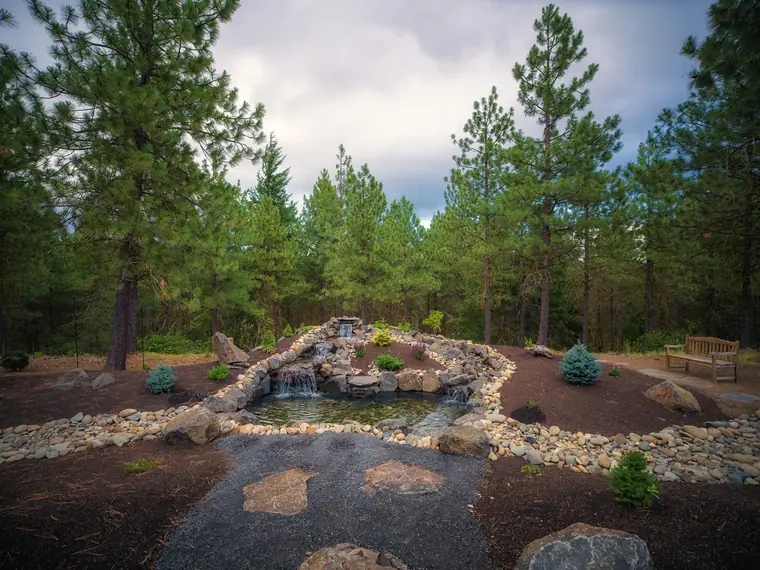 Wide view of the finished pond, waterfalls, flagstone path and planted beds
